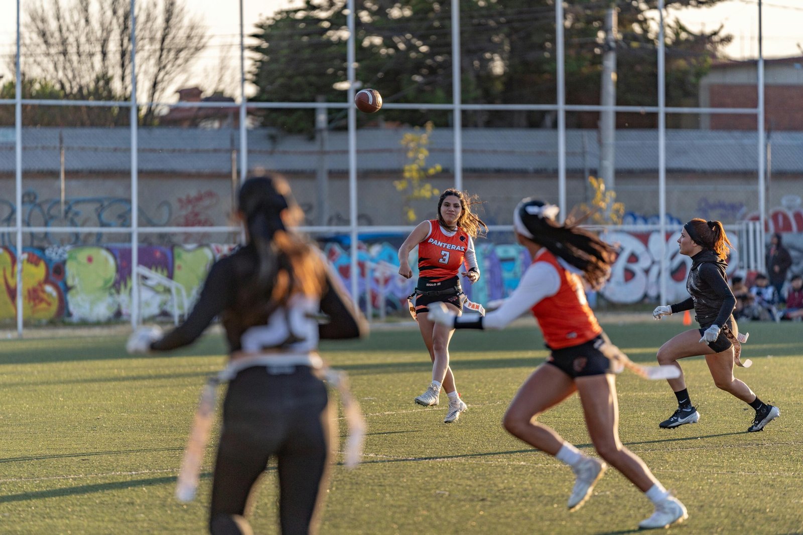 Dynamic women's flag football match with players in action, outdoors on a sunny day.